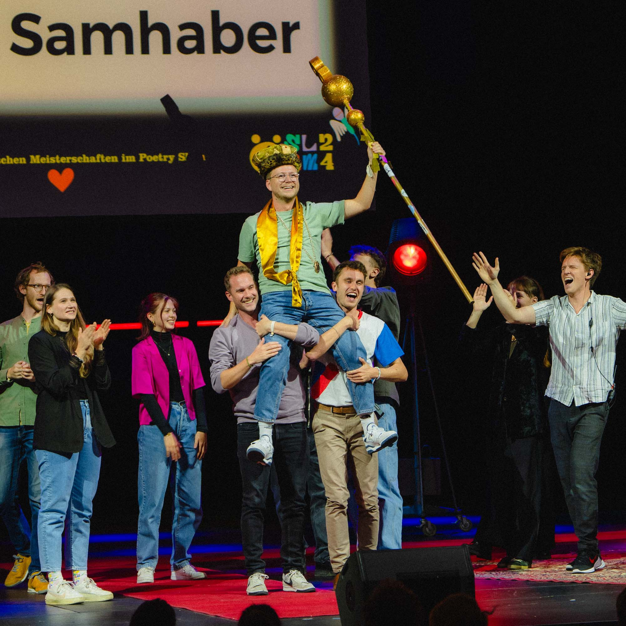 Siegesfoto beim Ö-Slam24: Sieger David Samhaber mit Krone, Zepter und Medaille auf den Schultern von Mike Hornyik und Emil Kaschka
